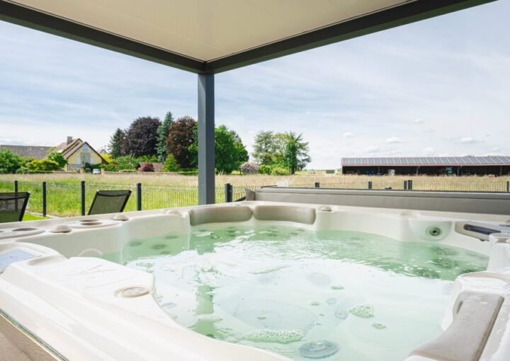 Jacuzzi sous une pergola avec vue sur les champs, logement La Moutonneraie en Alsace