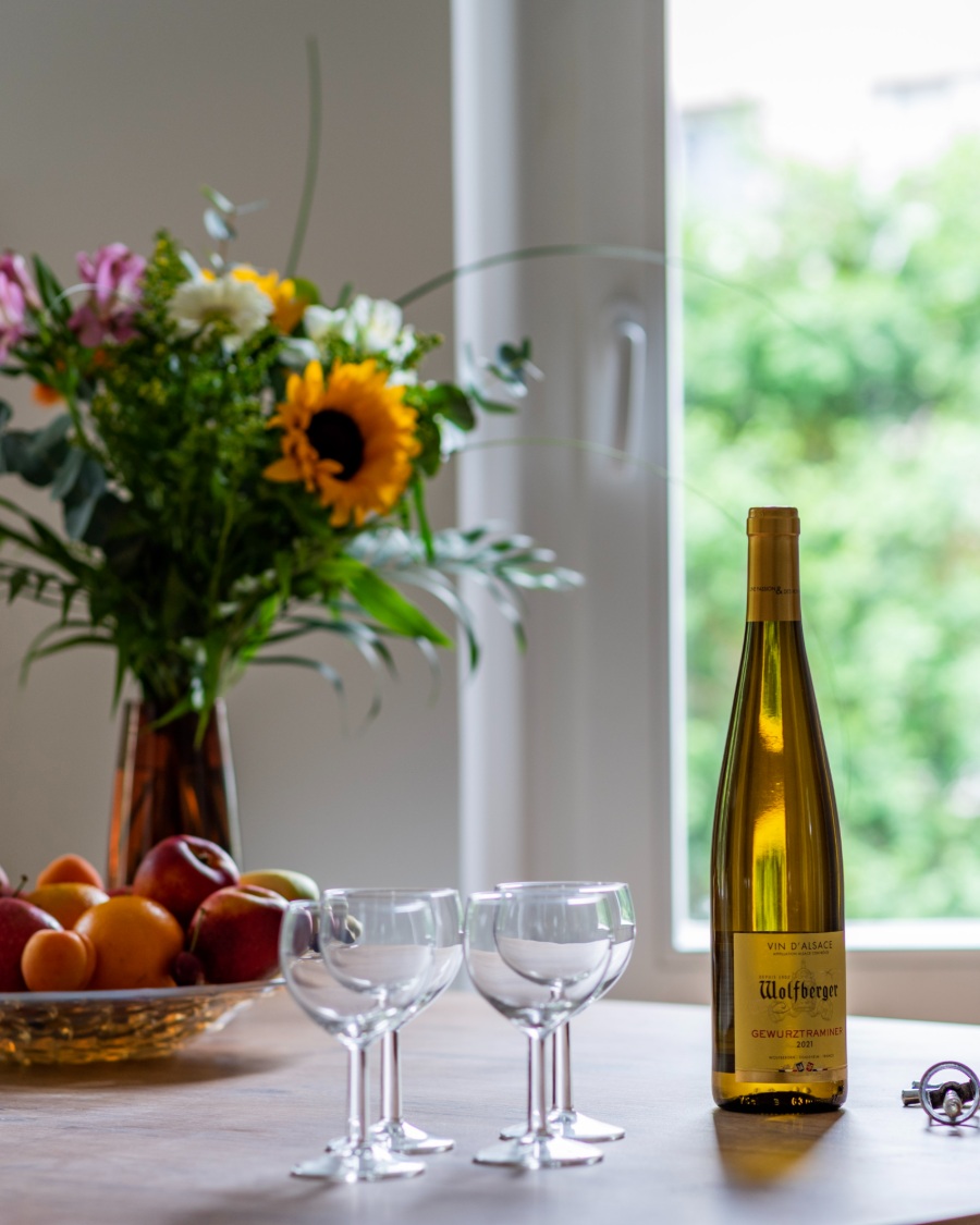 Kit d'accueil des voyageurs, bouquet, corbeille de fruits et vin d'Alsace sur la table d'un logement Golden Tree