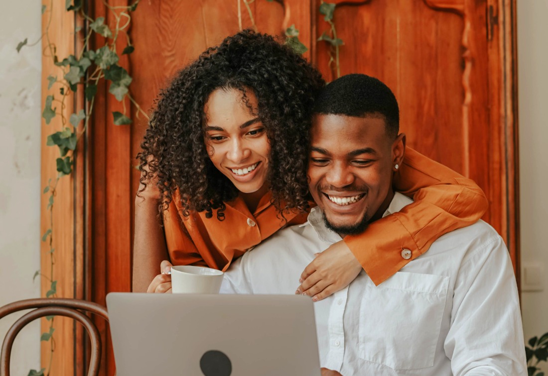 Couple de propriétaires souriant devant leurs revenus locatifs sur un ordinateur portable