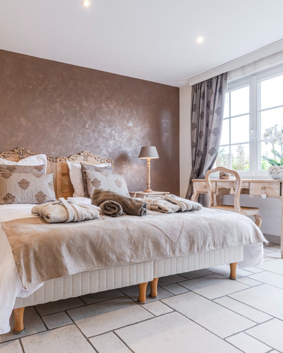 Lit fait avec serviettes et peignoirs posés dessus dans un logement Golden Tree prêt pour les voyageurs